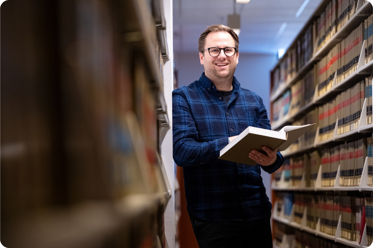man standing in library with open booik