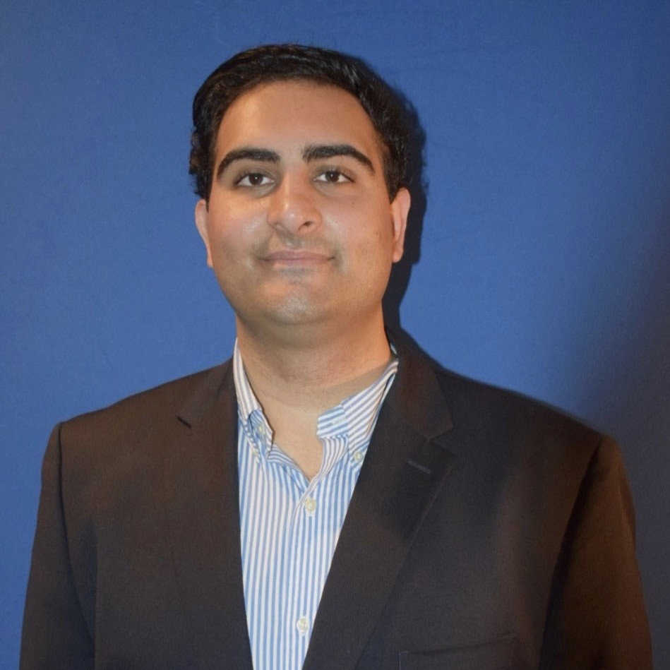 Headshot of a man wearing a black blazer in front of a blue background