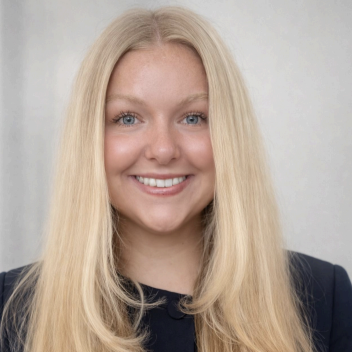 Headshot of a woman with blonde hair wearing a black top, standing in front of a gray background