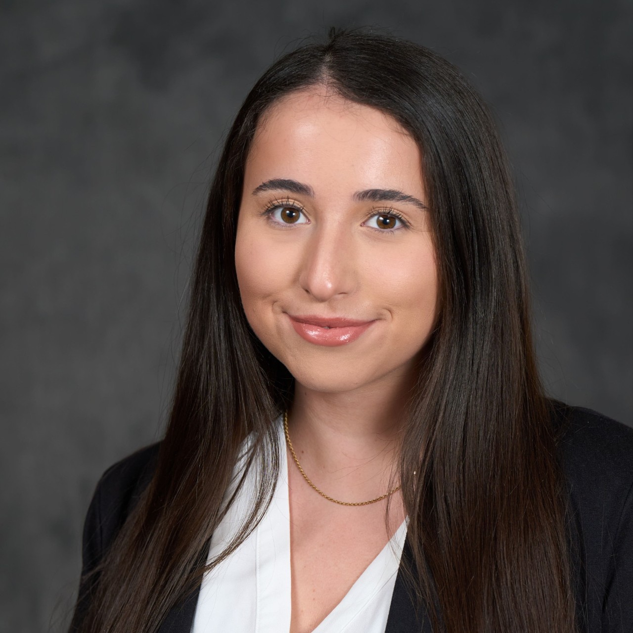 Headshot of a woman in a black blazer against a gray background