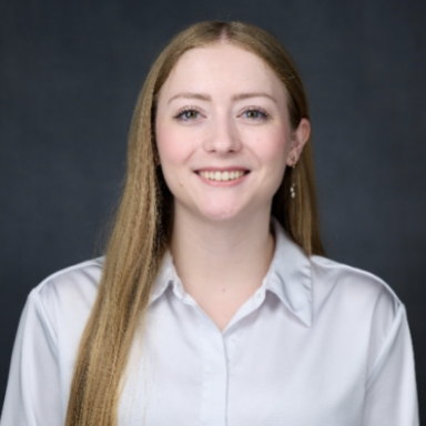 Headshot of a woman in a white blouse against a dark gray background