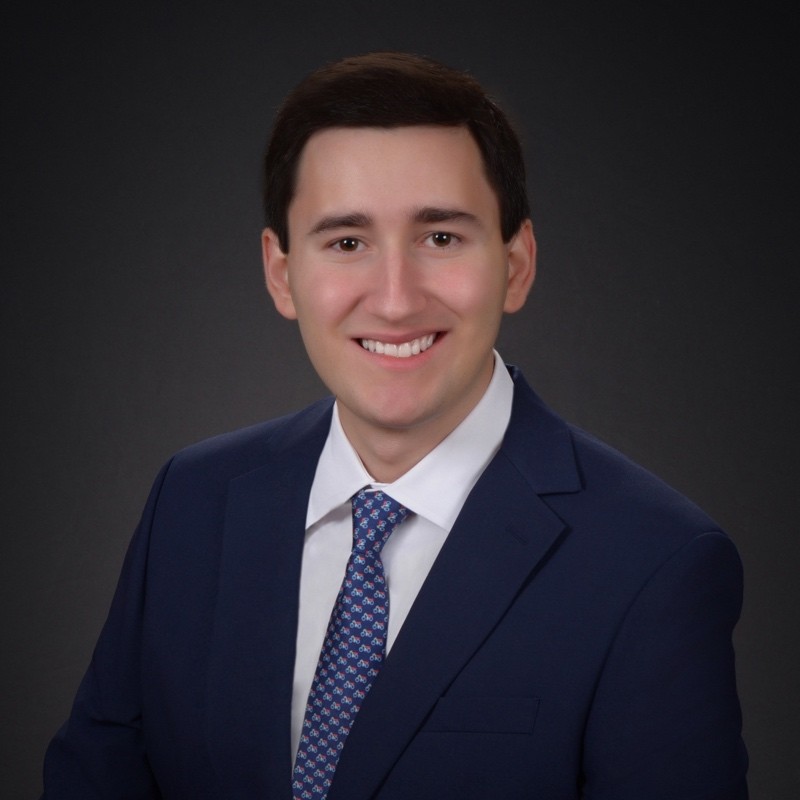 Headshot of a man in a suit against a gray background