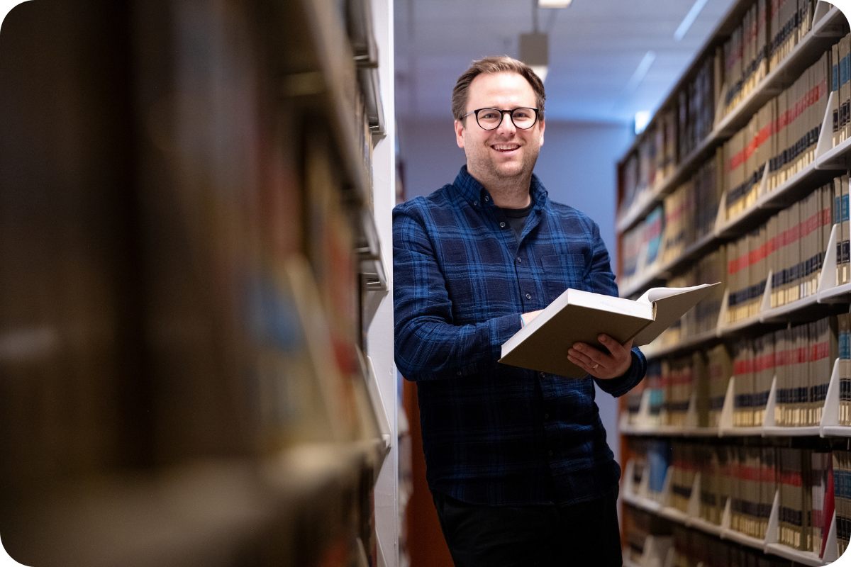Student standing in library with book