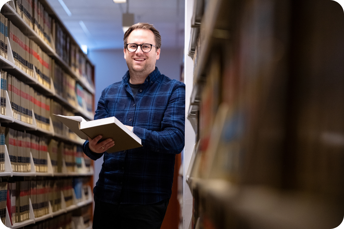 Student standing in library with book