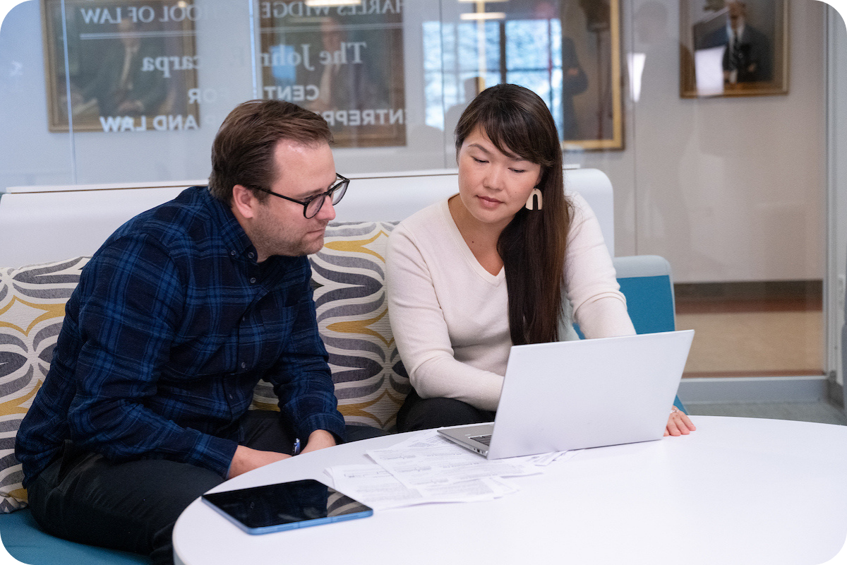 Two students talking over laptop