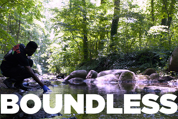 A student takes a water sample from a stream.