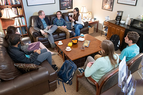 Students and their professor have a discussion in the Humanities lounge.
