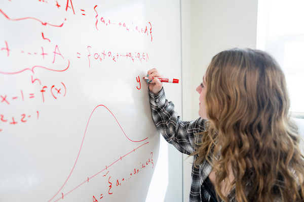 A student works on an equation on the whiteboard.