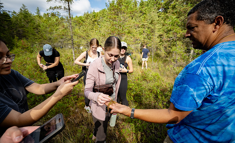 Students look at a sample in the field.