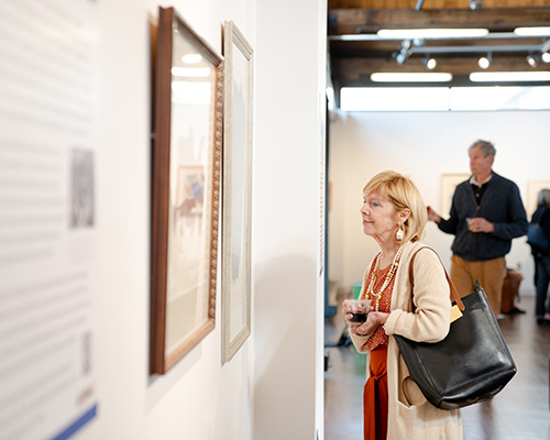 Patrons look at a piece at the exhibit, "Abstract Activism: Sam Maitin's Philadelphia."