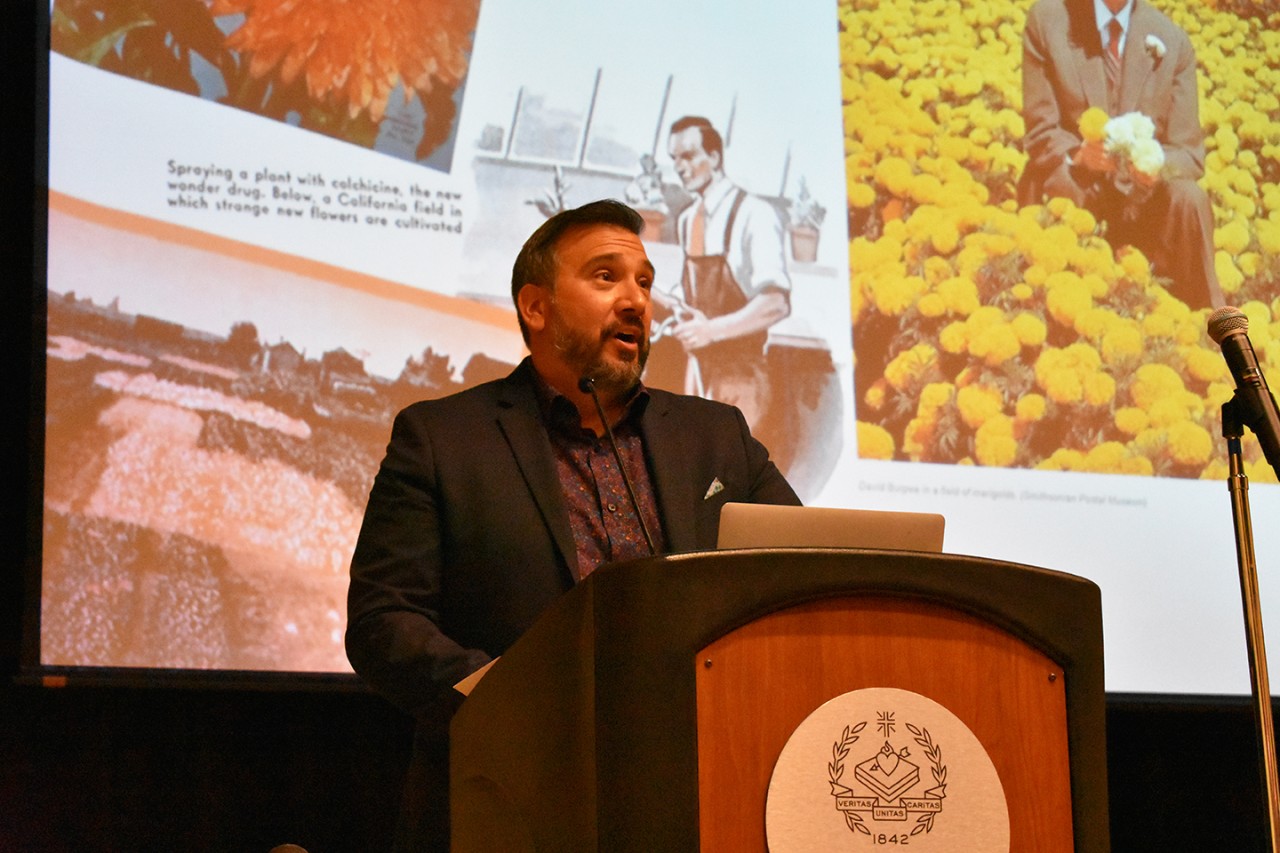 Graduate student presenting at the podium on stage at the Research Symposium