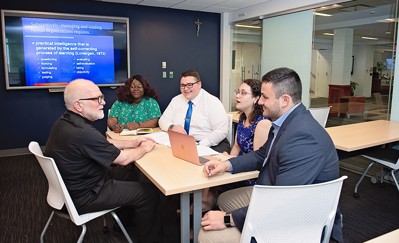 Graduate students sit around a table with a professor.