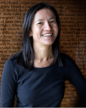 Tsering Wangmo stands in front of a background of printed text