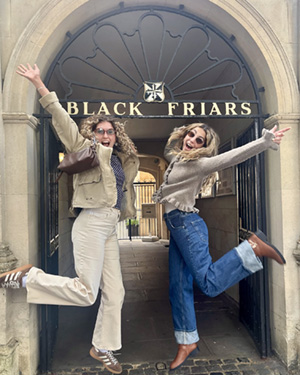 Two students jump outside a Blackfriars sign in Oxford