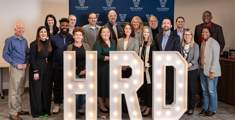 Faculty standing behind large 'HRD' display