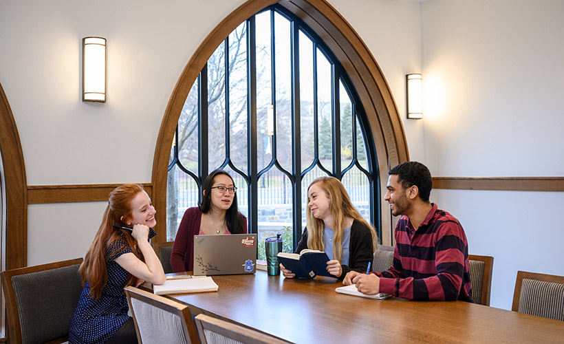 Students sit around a table in a discussion