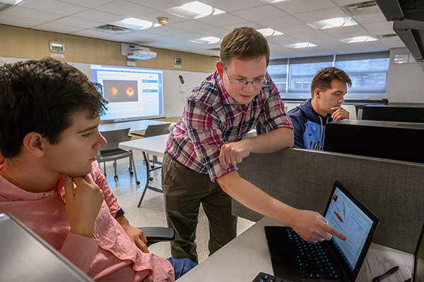 Physics professor Joey Neilsen works with a student in the lab.