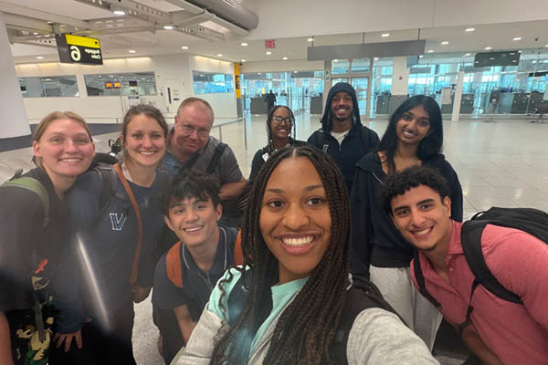 Group of students and staff posing for picture in airport