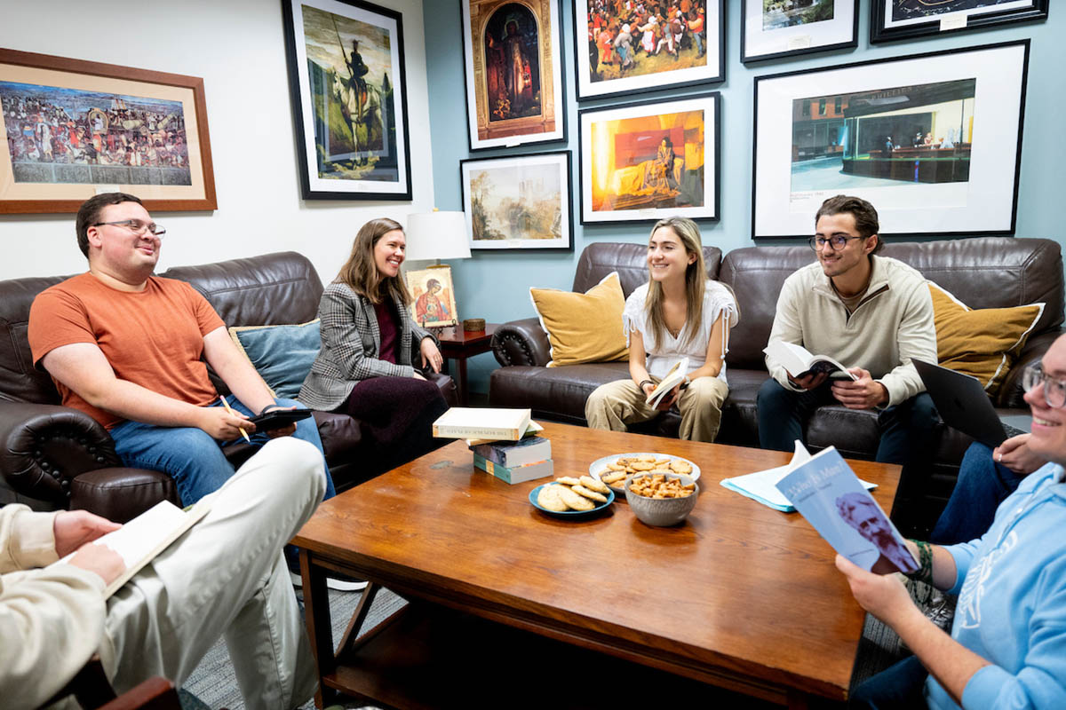 Students gathered around a table talking and holding books