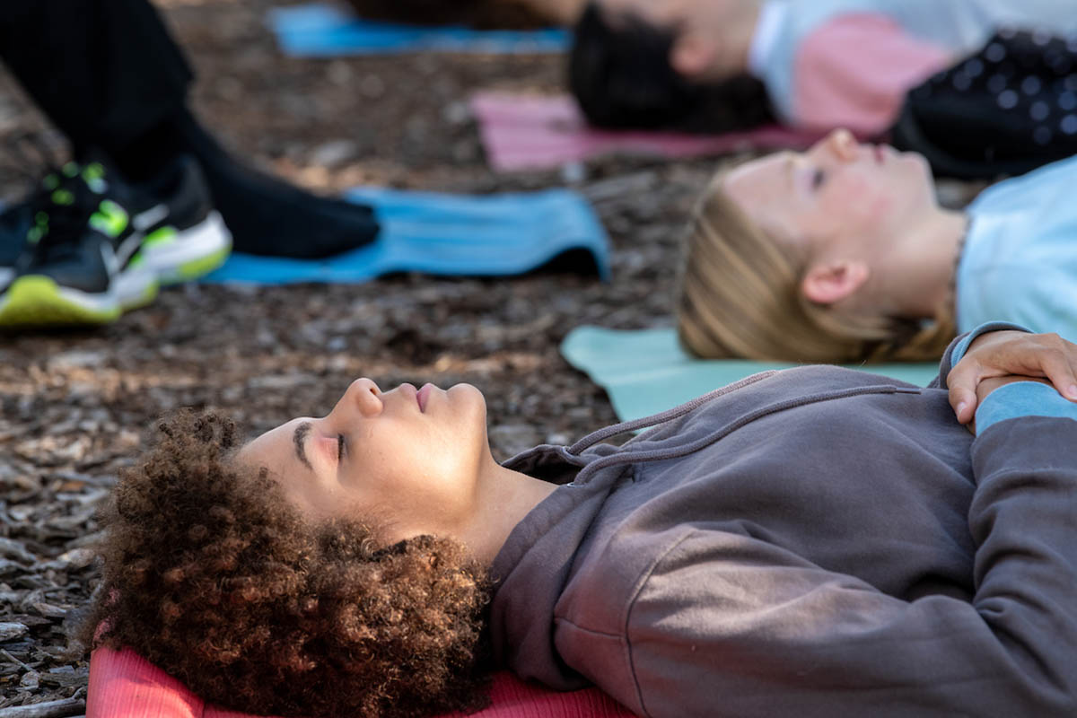 A female student laying down on a yoga mat with their eyes closed