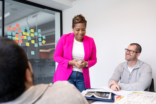 woman in pink jacket leads business meeting
