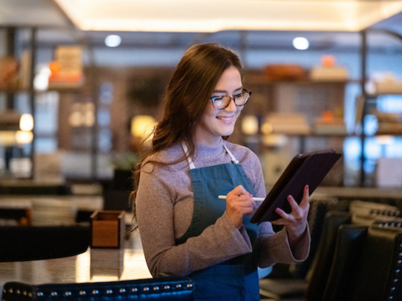 woman in glasses writing on a tablet