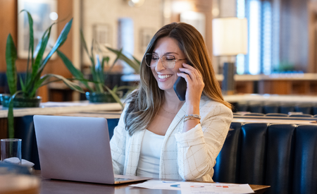 woman on the phone in front of a laptop
