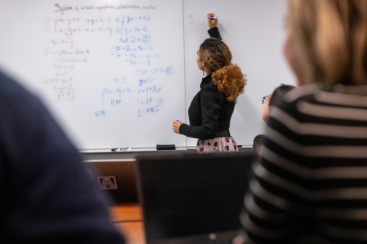 Student doing math on board in class