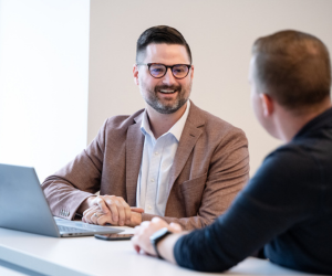 two colleagues conversing in front of a laptop