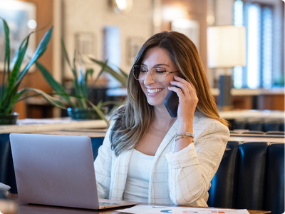 woman speaking on a cell phone while working on a laptop