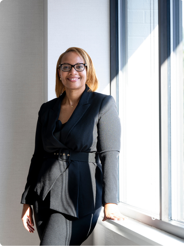 woman in glasses standing and smiling in front of the camera