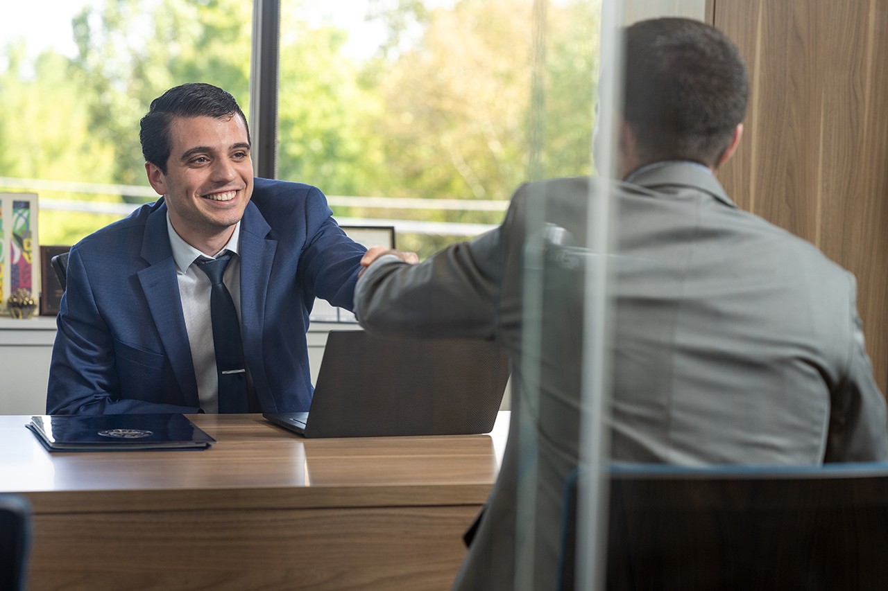 a man shaking hands with another man across a desk