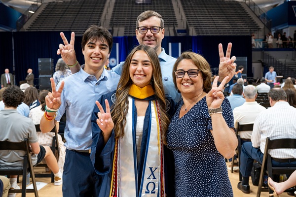 A family posing at graduation with their student