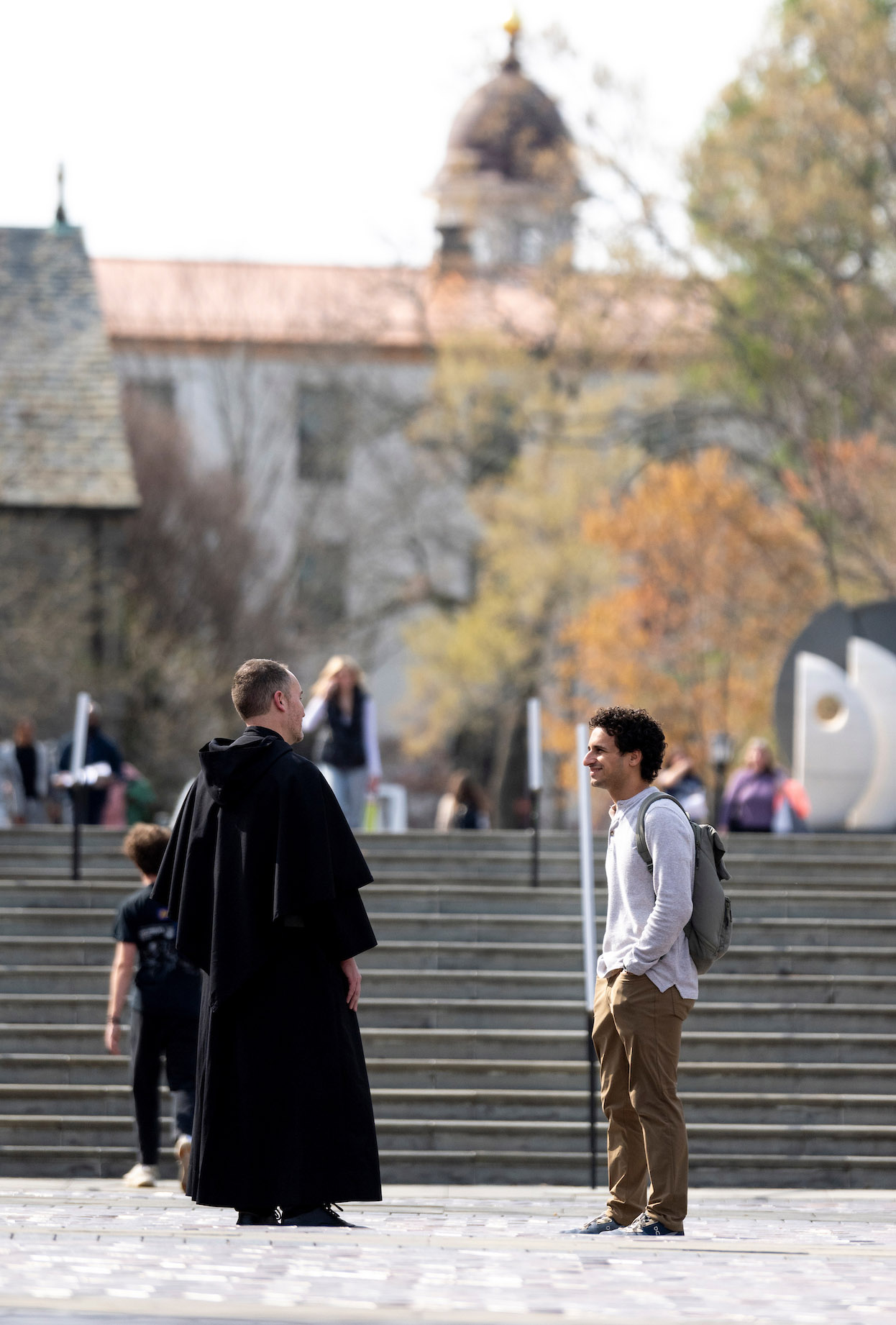 Augustinian talking to a student on campus