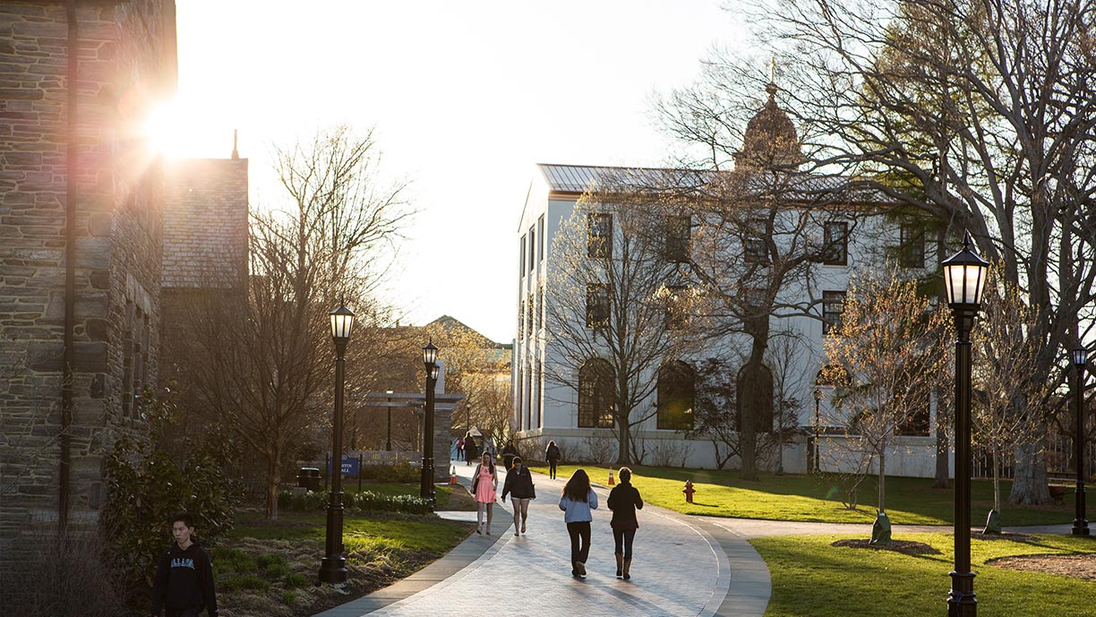 Students walking through sun-drenched pathway