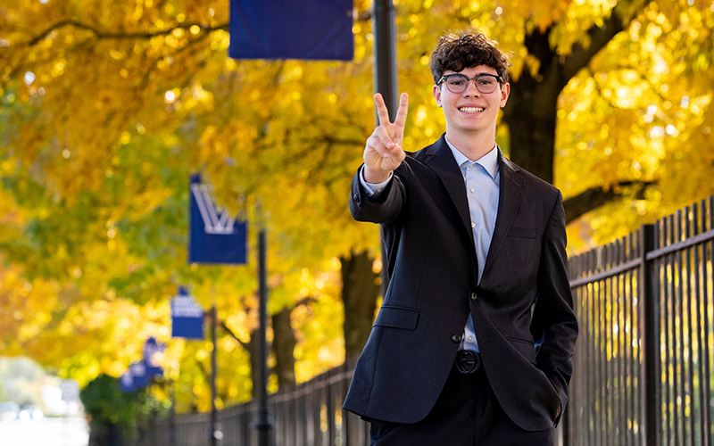A student dressed professionally giving Vs up.