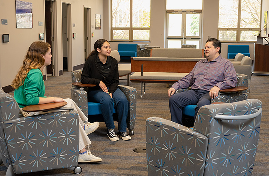 three people sitting in comfy chairs face each other