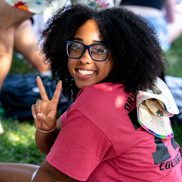 A female Orientation counselor makes a V sign with her fingers during New Student Orientation. 