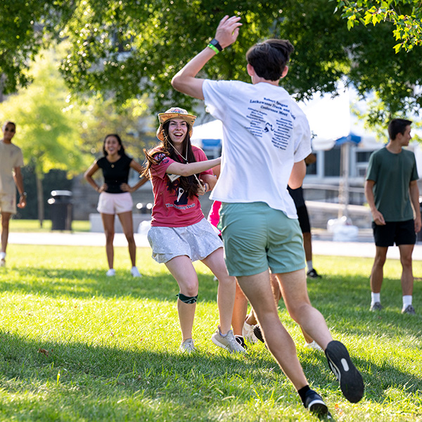 A female Orientation counselor plays outside with other students. 