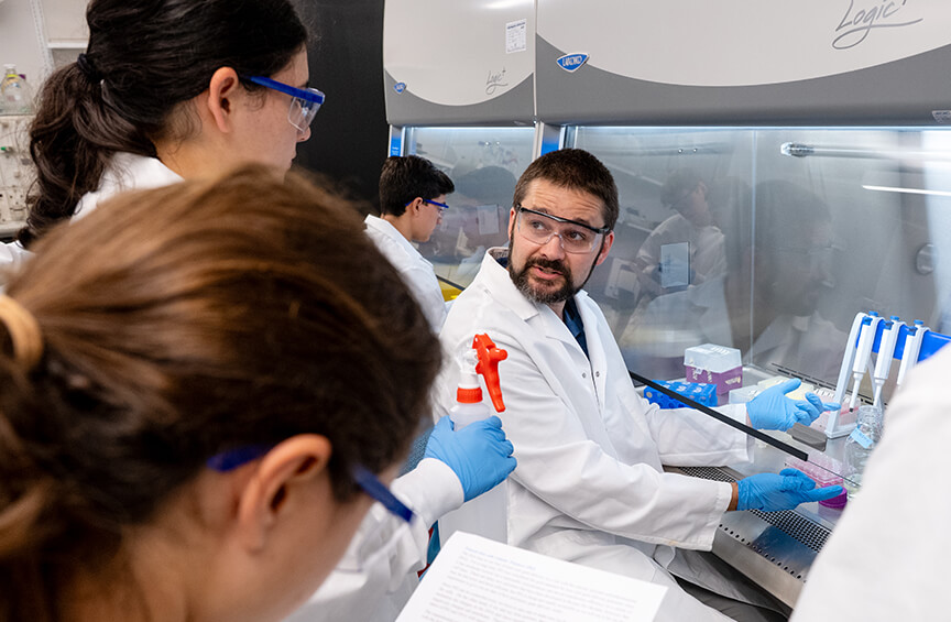 Jacob Elmer, PhD, works with students in a laboratory, teaching gene therapy research and methods.