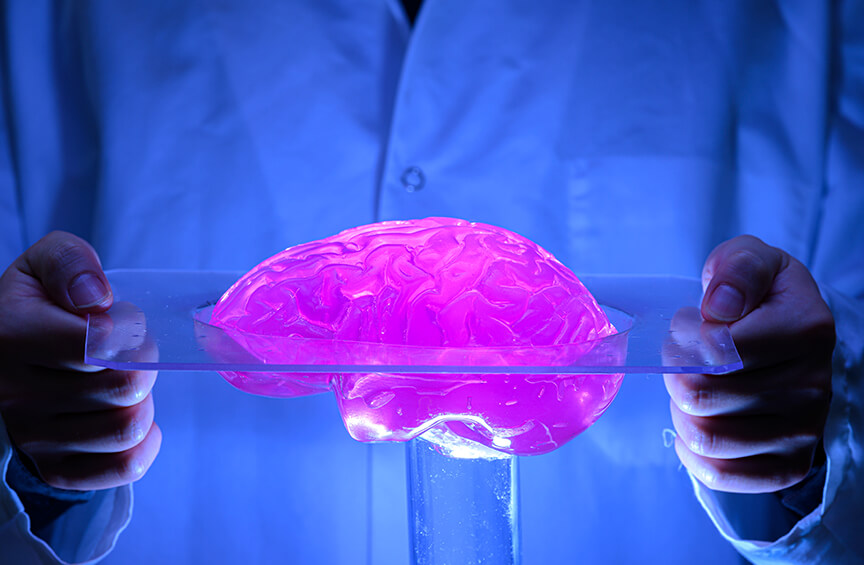 A person in a lab coat holds a glass plate displaying Dr. Wu’s glowing fuchsia pink “smart brain” invention.