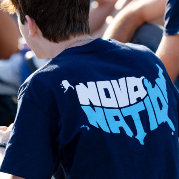 Villanova student with short brown hair seen from behind, wearing a T-shirt featuring an image shaped like the United States with the words ‘Nova Nation’ inside.