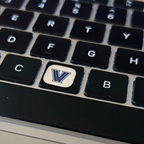 Close-up of a laptop keyboard with a Villanova ‘V’ sticker placed on the V key.