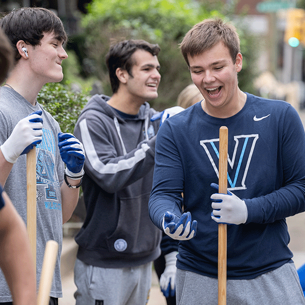 Three male Villanova student volunteers outside holding tools