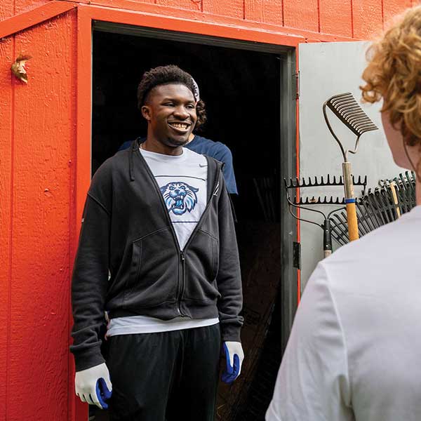 A male student stands in front of a brightly colored shed.