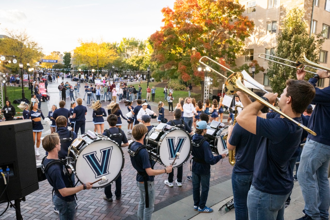 Villanova band and dancers perform during a campus event with students gathered nearby