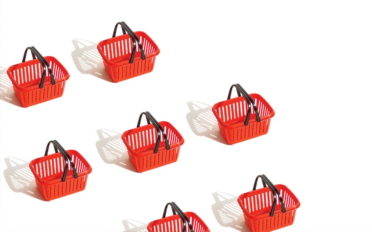 Six small red shopping baskets with black handles are arranged diagonally on a white background.