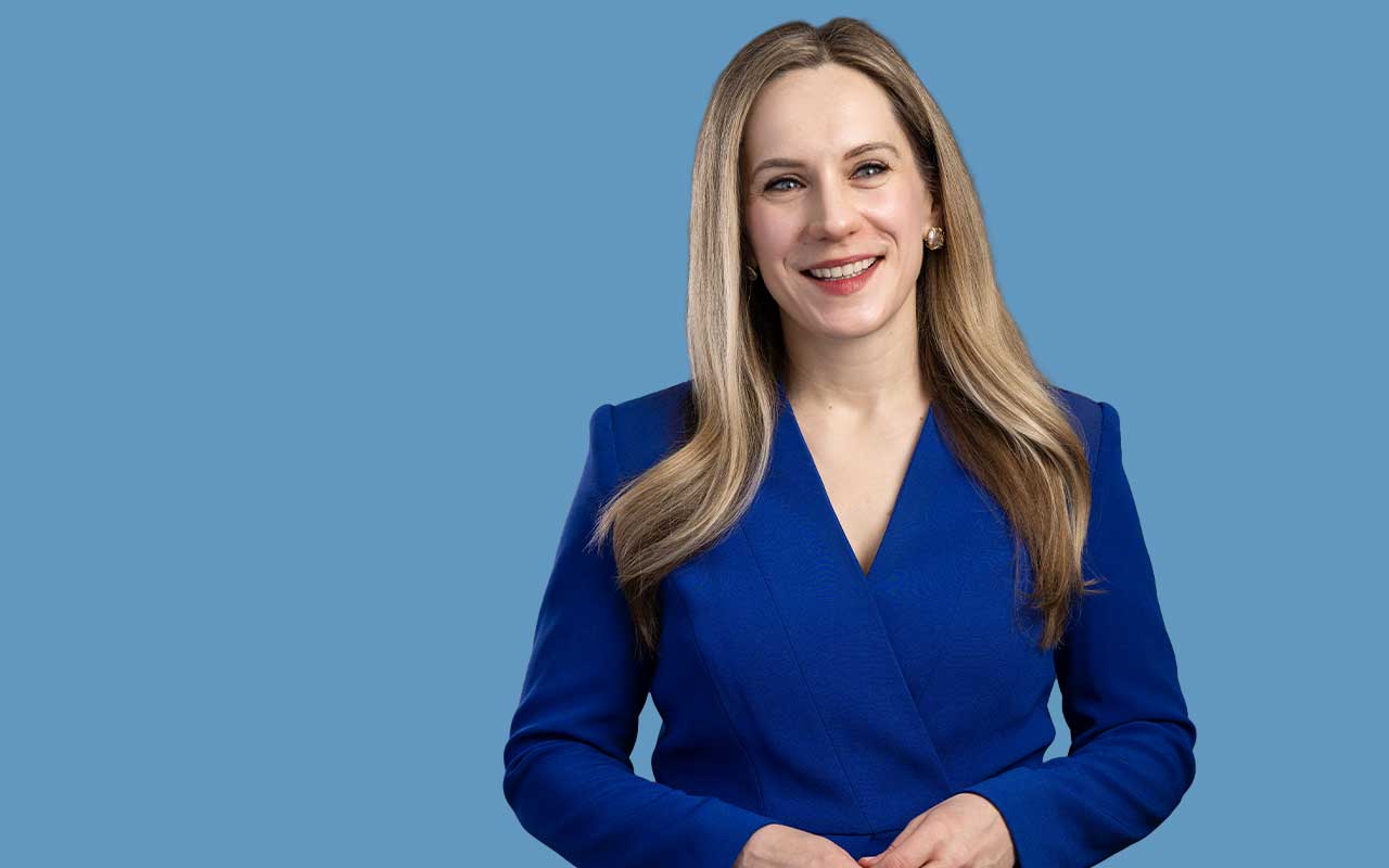 Catherine Stecyk poses for a portrait against a blue background.